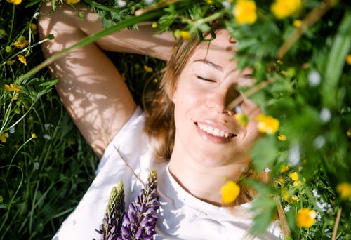 A woman lies in the grass. Here's how taurus season 2022 will affect each zodiac sign.