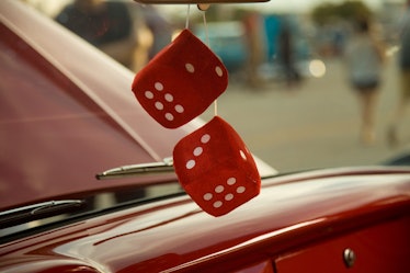 Fuzzy retro red dice hanging from a mirror in a red car