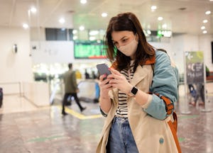 Portrait of a beautiful young woman on vacation arriving on the airport and using smartphone
