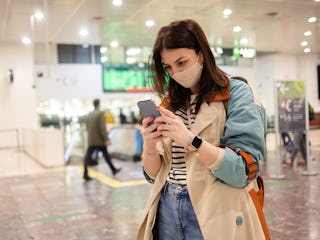 Portrait of a beautiful young woman on vacation arriving on the airport and using smartphone