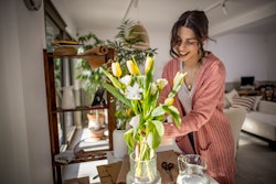 Young woman arranging her flowers at home on a beautiful sunny day. Your april 20 zodiac sign daily ...