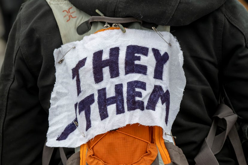 A protestor wears a piece of fabric with the pronouns 'they/them' pinned to them as Minneasotans hol...