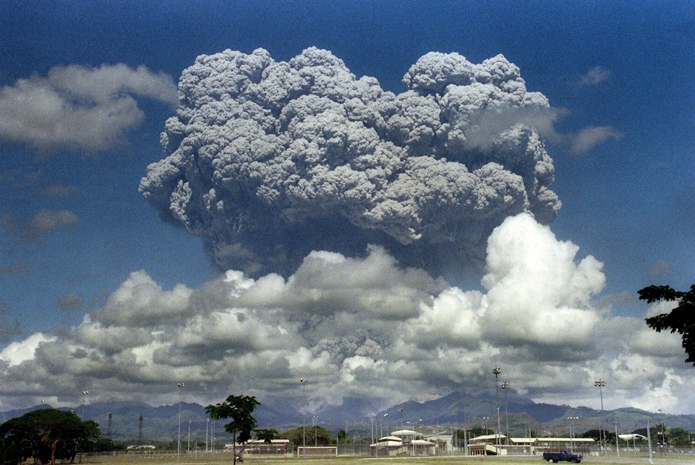 A giant volcanic mushroom cloud explodes some 20 kilometers high from Mount Pinatubo above almost de...