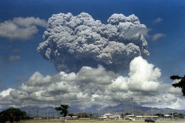 A giant volcanic mushroom cloud explodes some 20 kilometers high from Mount Pinatubo above almost de...
