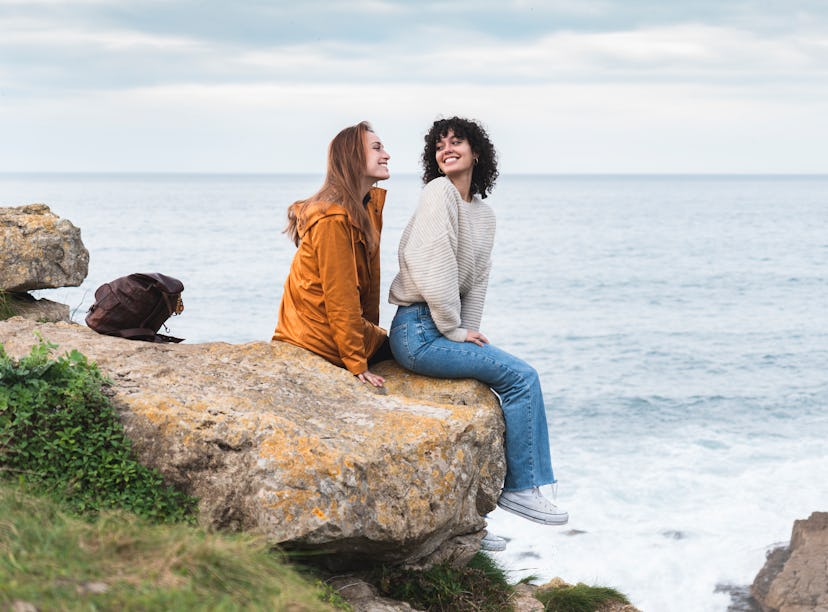 Two girls sitting on a rock while laughing