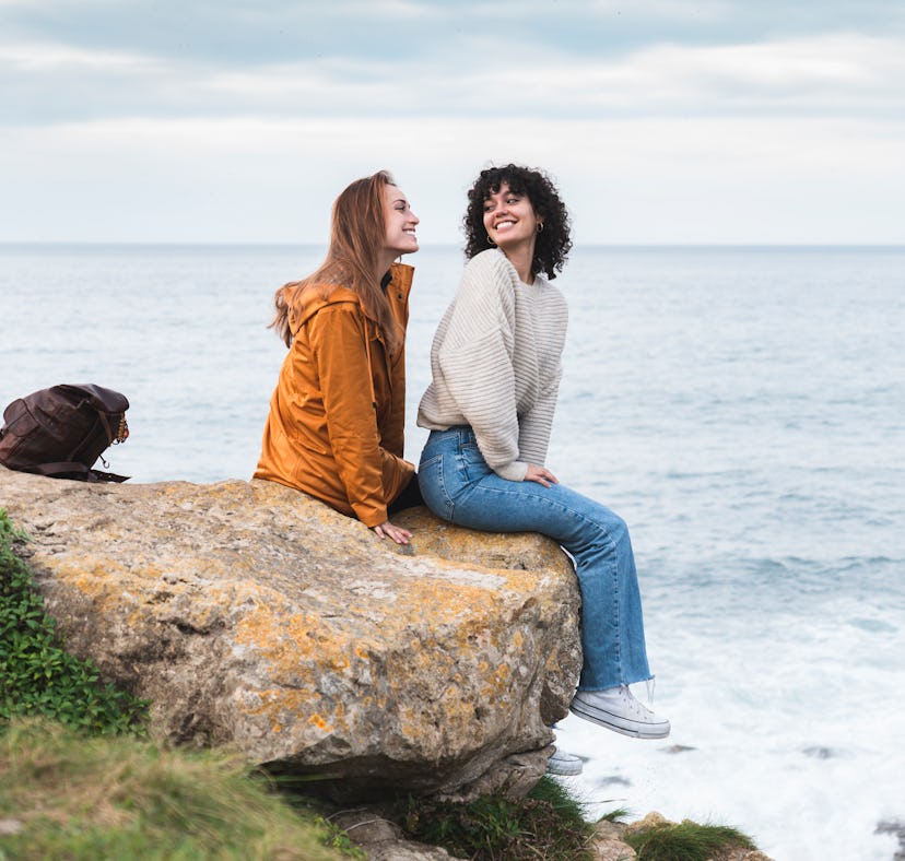 Two girls sitting on a rock while laughing