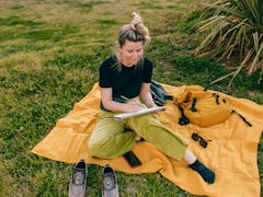 A woman sketches while on a picnic, which is one of the Earth Day activities on TikTok. 