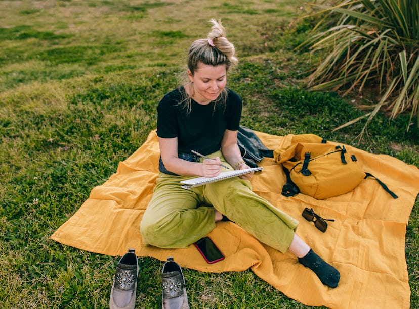 A woman sketches while on a picnic, which is one of the Earth Day activities on TikTok. 