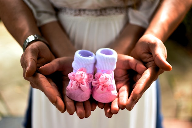A photo of you and your partner holding baby shoes is a cute Mother's Day baby announcement idea. 