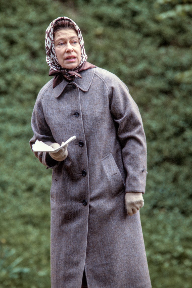 View of British monarch Queen Elizabeth II, in a silk headscarf, tweed overcoat, and woolen gloves, ...