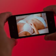 ILLUSTRATION - A young man holds a smartphone displaying an erotic photo of a young woman in Hanover...