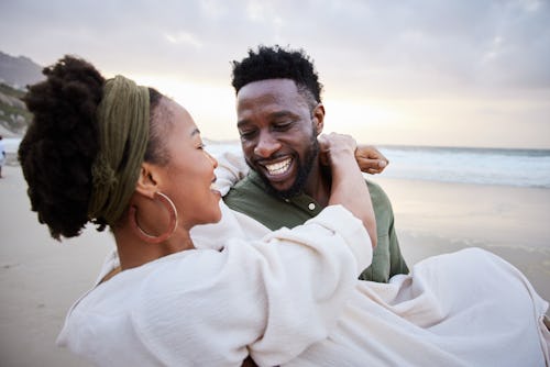 A couple laugh on the beach. Are Taurus and Capricorn compatible in relationships?