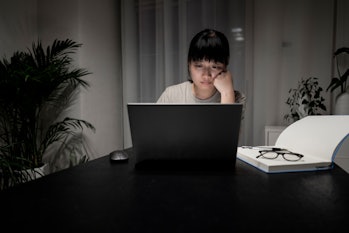 Young Asian women focused on working from home, working late at night on laptops at home. Home Offic...