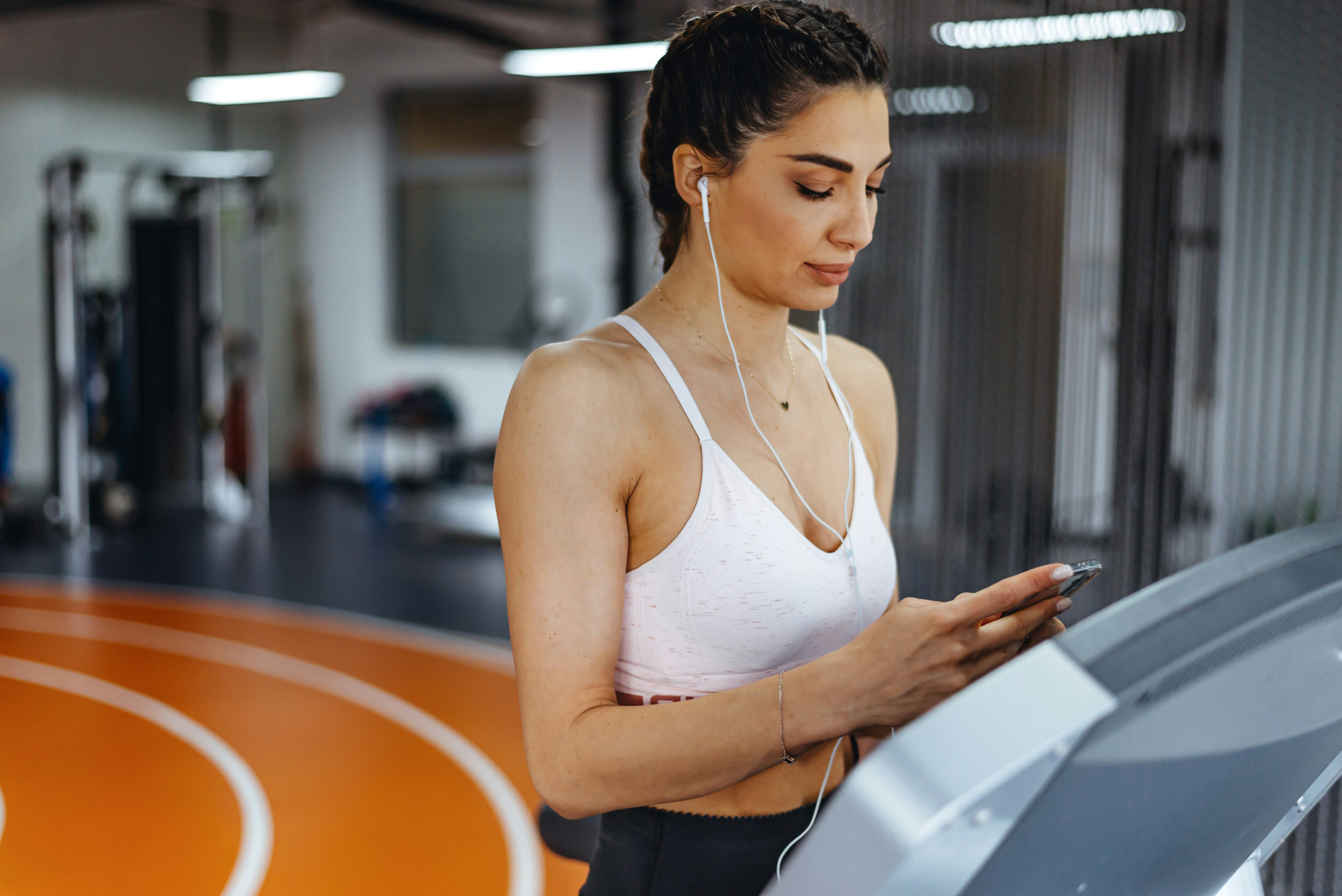 Young focused female working out at gym jogging on a treadmill. What are the benefits of tabata?