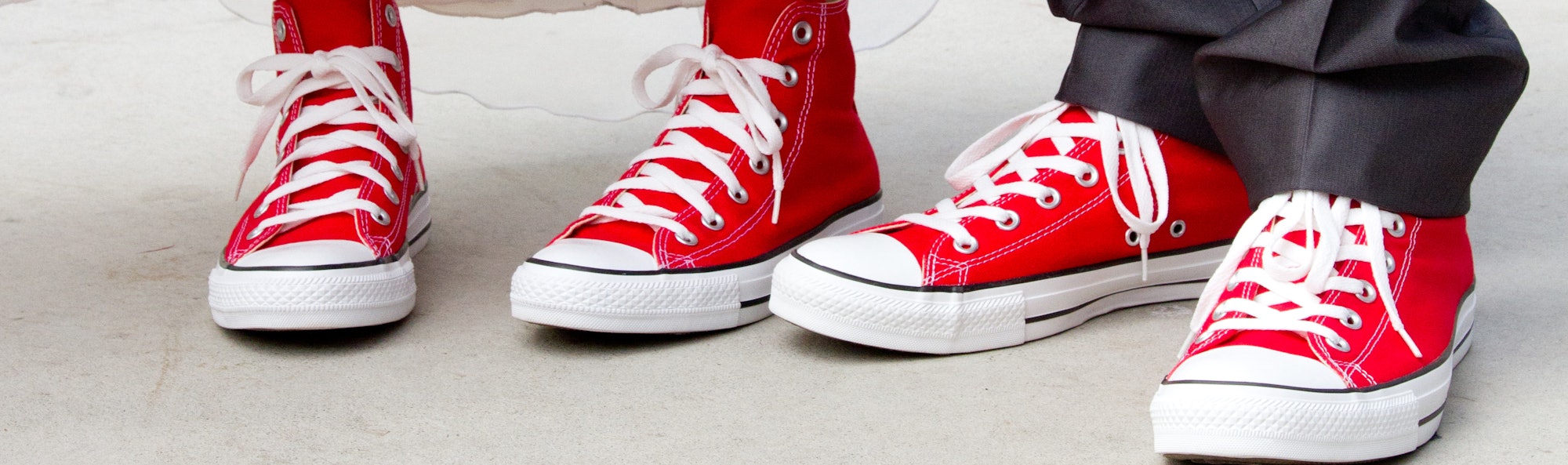 Bride and groom in wedding attire wearing red hi-top (high top) canvas sneakers with white laces.  L...