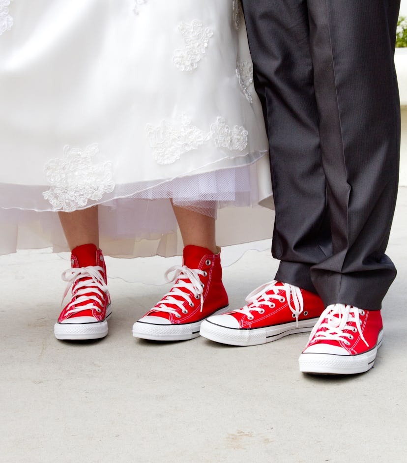 Bride and groom in wedding attire wearing red hi-top (high top) canvas sneakers with white laces. L...