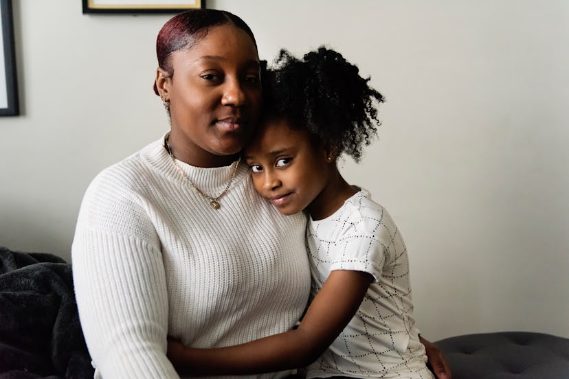 Portrait of mother and daughter in living room. Mom is in her thirties, daughter is 7 year’s old. Th...