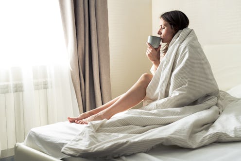 woman drinking coffee from her bed