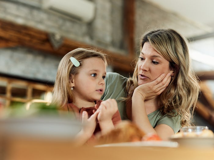 Young mother communicating with her small girl in dining room.