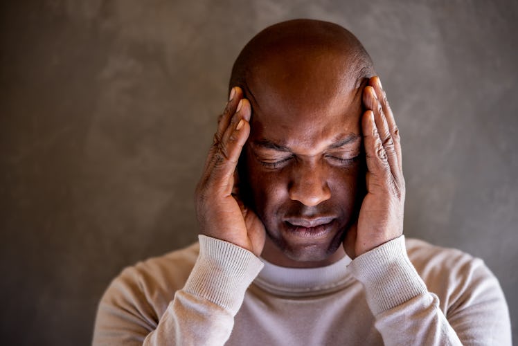 Portrait of a black man having a headache and grabbing his head - negative emotion concepts