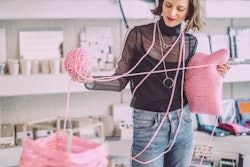 A woman knits with a ball of pink yarn. Here's your april 26 zodiac sign daily horoscope for 2022.