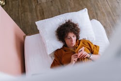 Above shot of a woman in the bed texting on her phone. Ginny Hogan's new book proposes 3 day rule of...