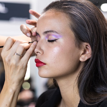 A model wearing pastel makeup prepares backstage prior to the catwalk of Jorge Vazquez during Merced...
