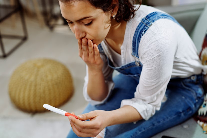 Worried woman holding pregnancy test during infertility awareness week
