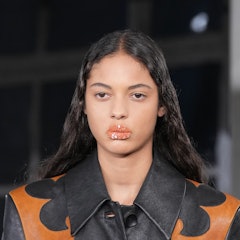A model wearing a glitter lip walks the runway during the Acne Studio Womenswear Spring/Summer 2022 ...