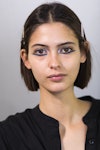 A model wearing graphic floating eyeliner prepares backstage prior to the catwalk of Claro Couture d...