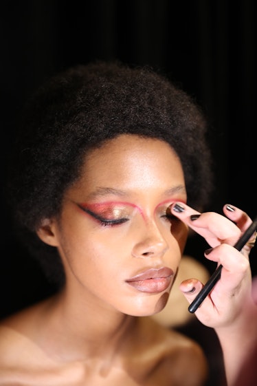 A model wearing duochrome eyeshadow prepares backstage for the at the LaQuan Smith Fall/Winter 2022 ...