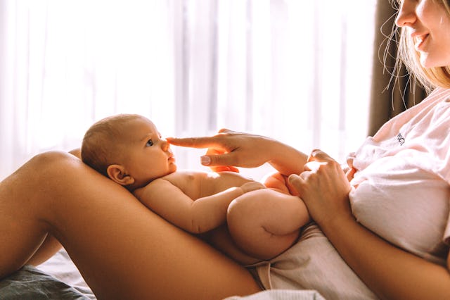 Young mother and baby girl smiling at each other in bed
