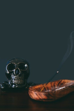 Close-up of incense burning next to decorative skull