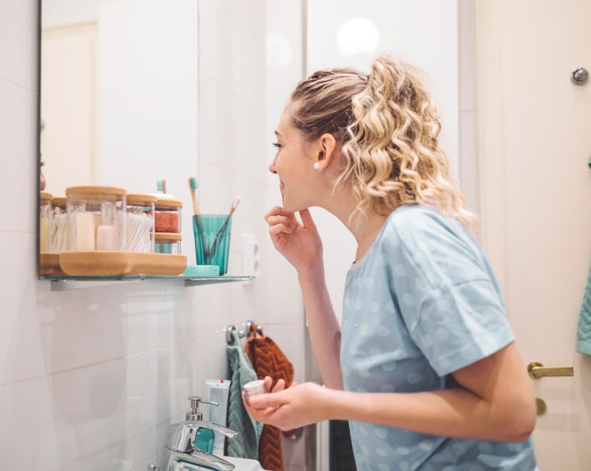 woman examining face in mirror, what to know about niacinamide during pregnancy