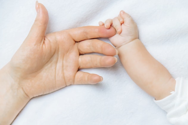 A photo of mom and newborn baby holding hands is a cute Mother's Day baby announcement idea.