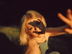 young woman reaches for camera as shadows fall on her face thinks about the spiritual meaning of the...