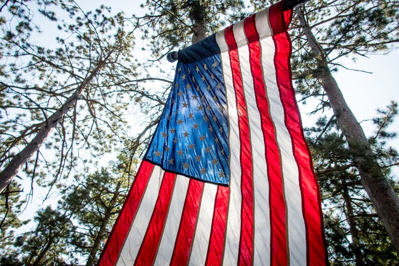 Looking up from a low angle at an American flag backlit from the sun.