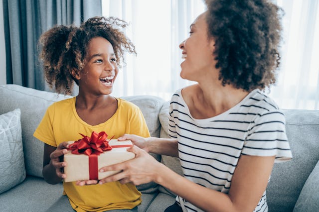 Shot of a loving mother giving her daughter a gift. Mother surprise her little girl with present whi...