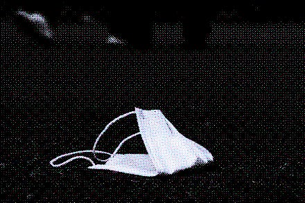 Used lost protective medical face mask on the ground. A disposable mask is lying on the sidewalk out...