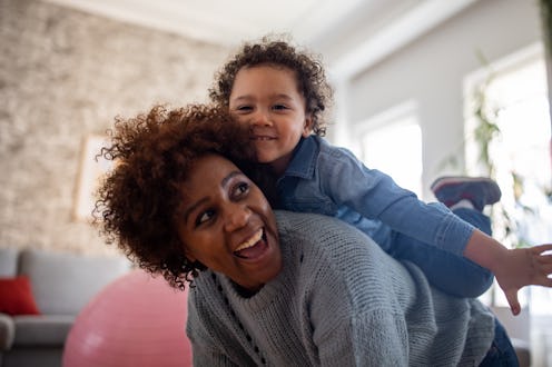 Playful mother and son Black ethnicity playing together in the living room