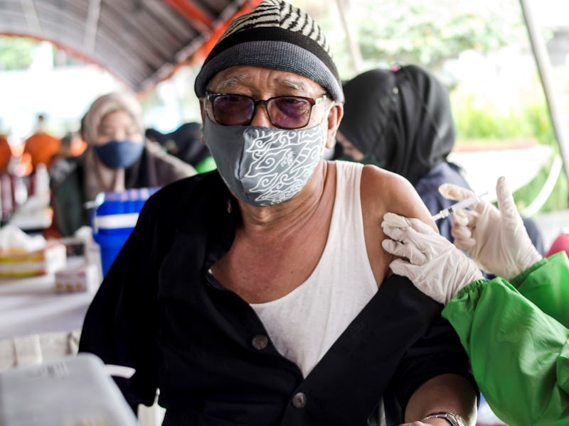 A health worker inoculates an elderly man with a booster dose of COVID-19 vaccine in Bandung, West J...