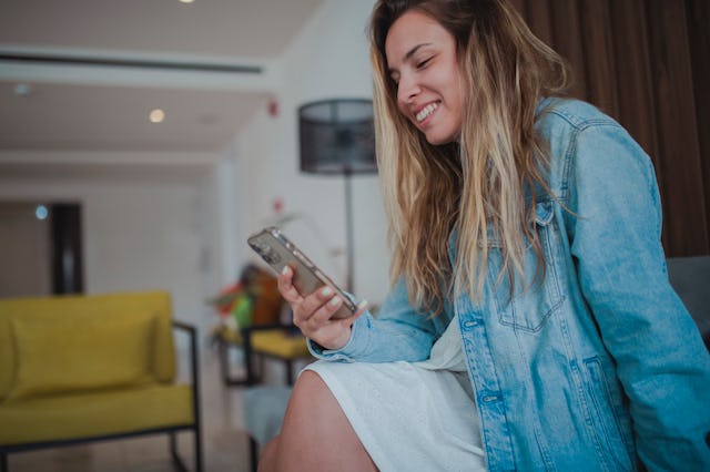 A woman looks at her phone -- Google now allows users to block certain types of ads about sensitive ...