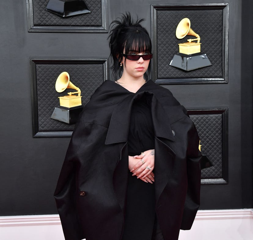 Billie Eilish wears a black asymmetrical dress with flatform shoes on the Grammys 2022 red carpet.