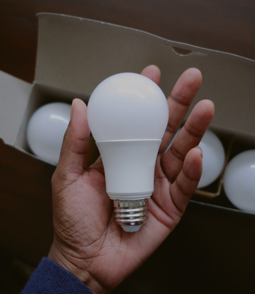 High angle view of unrecognizable black woman holding new LED light bulb