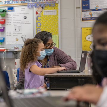 A second grade teacher showing a student something on the computer. 1 in 5 teachers have reported de...