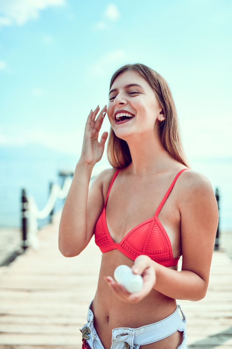 Smiling Female Putting Sunscreen Before Sunbathing