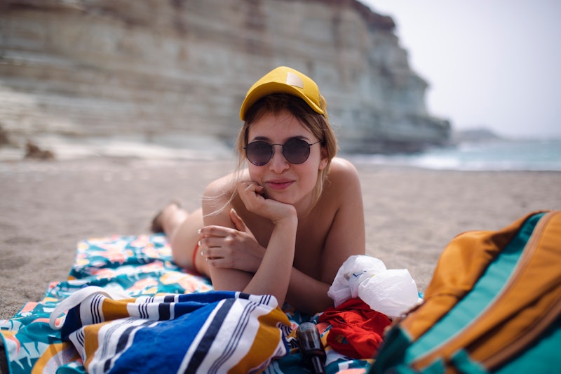 A smiling woman enjoys the beach, resting and sunbathing.
