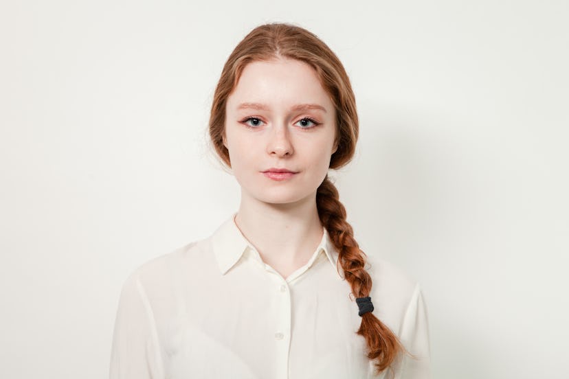 Close-up studio portrait of an attractive 20 year old red-haired woman in a white shirt on a white b...