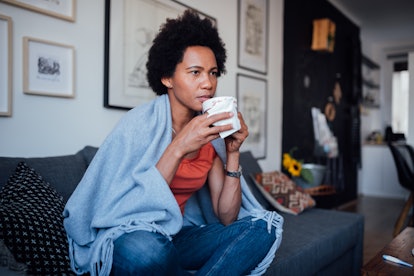 woman on couch, warming up with blanket and tea