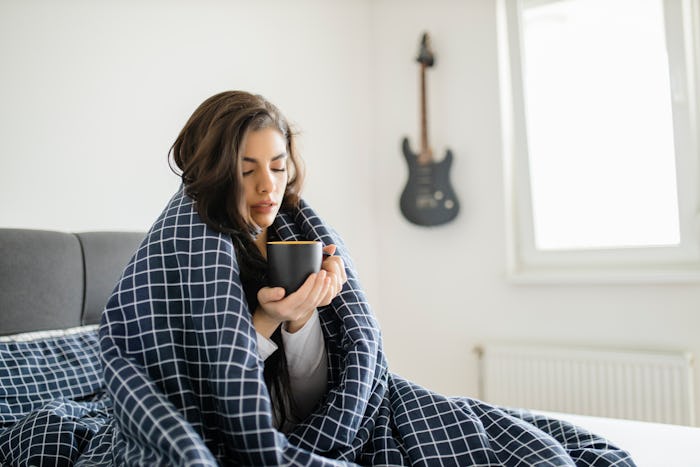 woman warming up with tea and blanket